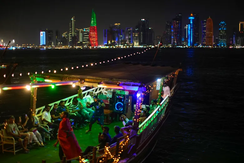 Люди танцуют в деревянной лодке на морской набережной Корниш в Дохе, Катар