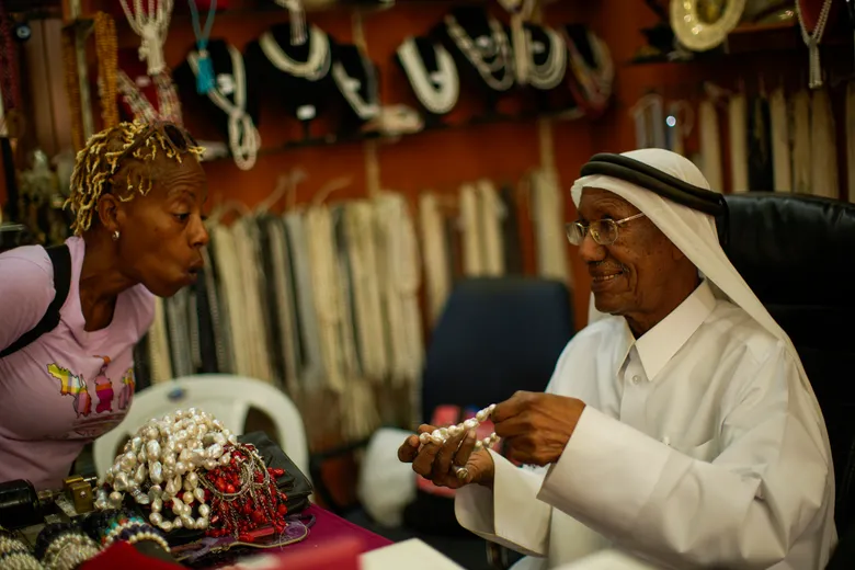 Бывший ныряльщик за жемчугом Саад Исмаил разговаривает с клиентом в своем магазине жемчуга в Дохе, Катар